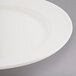 A close up of a Libbey ivory porcelain plate with a rim on a gray surface.