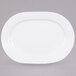 A CAC Garden State bone white porcelain platter with a curved edge on a gray surface.
