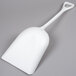 A white plastic shovel on a gray surface.
