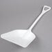 A white plastic Carlisle Sparta ice shovel with a handle.