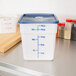 A white plastic Cambro CamSquares food storage container with a blue lid.