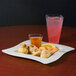 A Fineline ivory plastic square plate with food and a drink on a table.