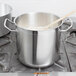 A silver Vollrath stainless steel stock pot with a wooden spoon inside.