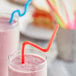 A glass of smoothie with a Choice jumbo neon crazy straw in it.