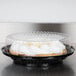 A pie in a black plastic container with a clear high dome lid.