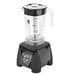 A black Waring commercial blender with a clear blender jar and lid.