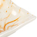 A white square sauce dish with an orange and gold orchid swirl pattern.
