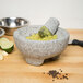 A Fox Run Granite Mortar and Pestle with lime and garlic inside.