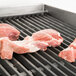 Raw meat cooking on an APW Wyott lava rock charbroiler.