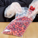 A person in gloves holding a LK Packaging plastic bag of cranberries.