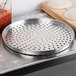 An American Metalcraft perforated aluminum pizza pan on a counter.