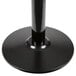 A Lancaster Table & Seating black cast iron round table base with a black metal pole and round base.