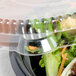 A plastic container with a clear dome lid containing a salad.