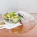 A Dart clear plastic bowl with a salad in it.