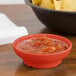 A GET Rio Orange melamine salsa dish filled with salsa on a table next to a bowl of chips.