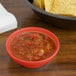 A bowl of salsa and a bowl of chips on a table.