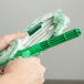 A hand holding a Unger Monsoon Plus StripWasher with a green and white mop.