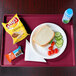 A Cambro cherry red hospital dietary tray with a sandwich, vegetables, and a drink on it.