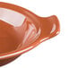 A Libbey terracotta handled baker with a brown liquid in it.