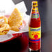 A bottle of The Original Louisiana Brand Original Hot Sauce next to a basket of fried fish.