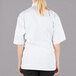 A woman wearing a white Mercer Culinary short sleeve chef jacket with cloth knot buttons.