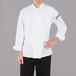 A man wearing a Mercer Culinary white long sleeve chef jacket with cloth knot buttons.