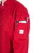 A person wearing a Mercer Culinary red long sleeve chef jacket with a pocket on the back.