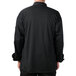 The back of a person wearing a black Mercer Culinary Millennia Air chef jacket with a full mesh back.