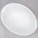 An Arcoroc deep oval porcelain bowl with a white rim on a gray surface.