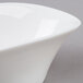 A close-up of an Arcoroc white porcelain deep oval bowl with a curved edge.