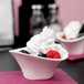 An Arcoroc deep oval porcelain bowl filled with fruit and whipped cream.