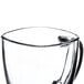 A close-up of a clear glass Libbey square mug with a handle.