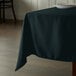 A table with a hunter green Intedge square tablecloth on it.