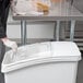 A person wearing white gloves slides a lid onto a white Baker's Mark ingredient storage bin.