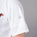 A person wearing a Mercer Culinary white short sleeve cook shirt with a red pen in the pocket.