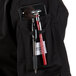 A Mercer Culinary Millennia Women's Black chef jacket with a cell phone and pen in the pocket.