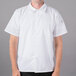 A man wearing a Mercer Culinary Millennia white short sleeve cook shirt with full mesh back.