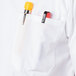 A white Mercer Culinary Millennia cook shirt pocket with a pen and a yellow object in it.