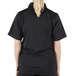A woman wearing a Mercer Culinary Millennia black cook shirt with full mesh back.