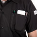 A person wearing a Mercer Culinary Millennia black cook shirt with a full mesh back and a pocket full of tools.