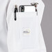 A white Mercer Culinary Millennia women's cook jacket with a pocket and pen.