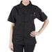 A woman wearing a black Mercer Culinary Millennia cook shirt with a mesh back.