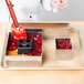 A metal tray with a Matfer Bourgeat square wedding cake frame filled with red jelly.