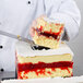A person cutting a cake using a Matfer Bourgeat square cake frame.