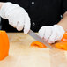 A person in a white glove using a Mercer Culinary Renaissance forged utility knife to cut a bell pepper.