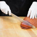 A person in white gloves using a Mercer Culinary Renaissance slicer to cut ham.
