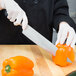 A person using a Mercer Renaissance chef's knife to cut a bell pepper.
