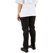 The legs of a person wearing Mercer Culinary black pleated chef trousers with a white shirt.