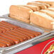 A tray of hot dogs and buns on a counter.