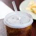 A plastic lid with a straw slot on a plastic cup with a straw in it.